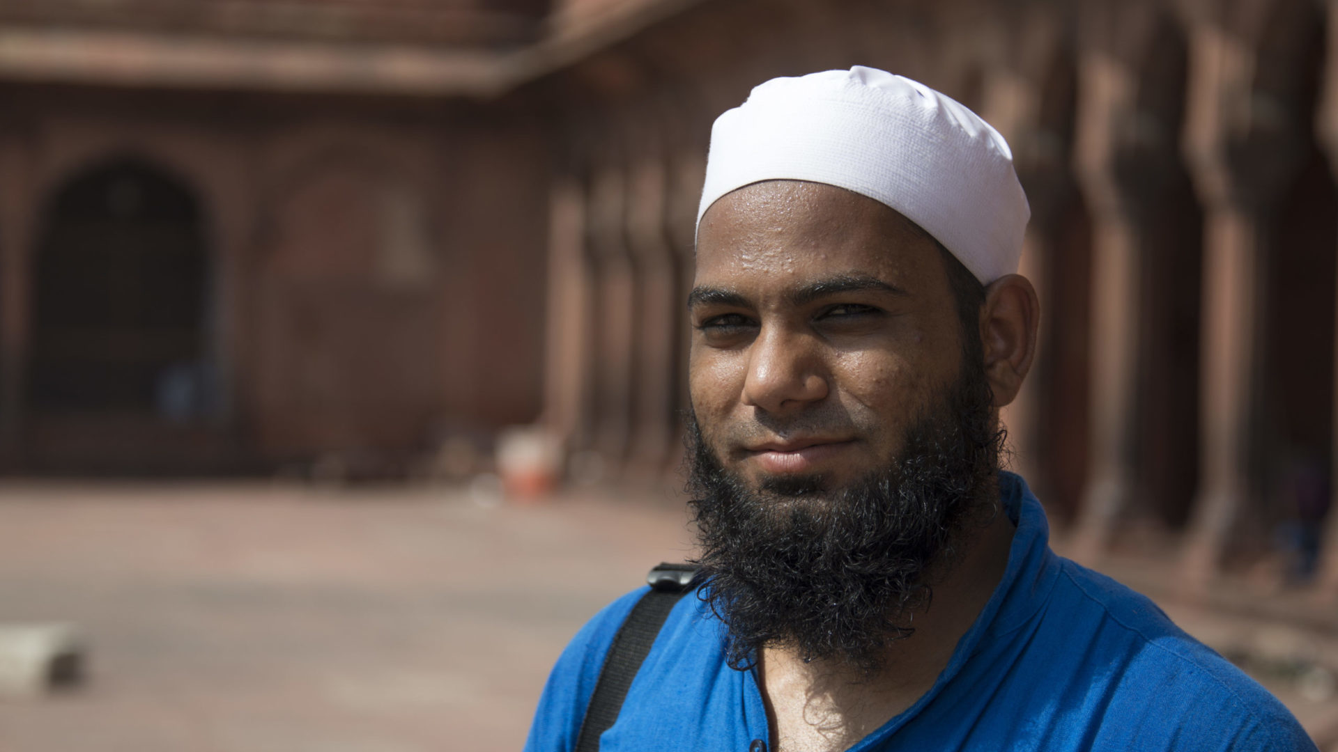 A portrait of a man with a blue shirt and a white hat.