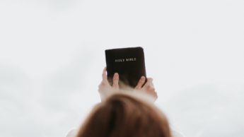 A woman holding up the Bible towards the sky as she prepares to share the gospel with Mormons.