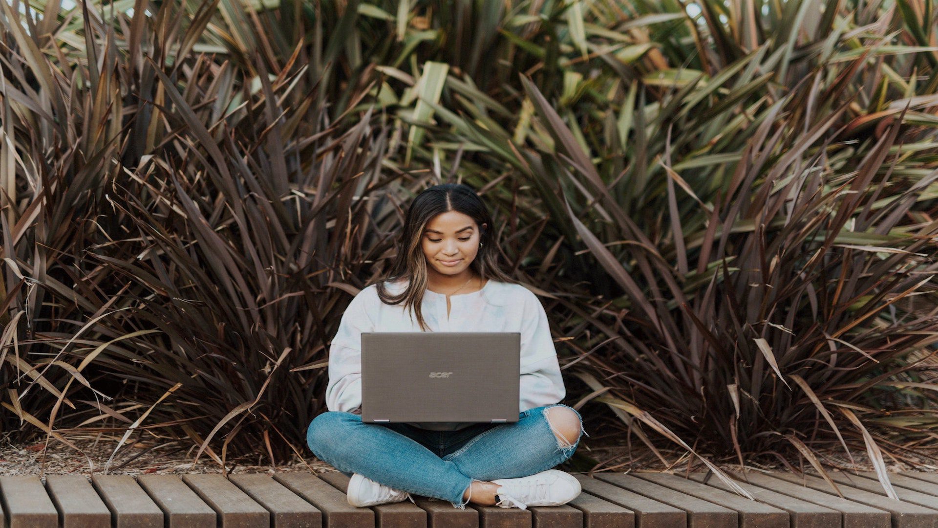 A woman sitting outside on her laptop.
