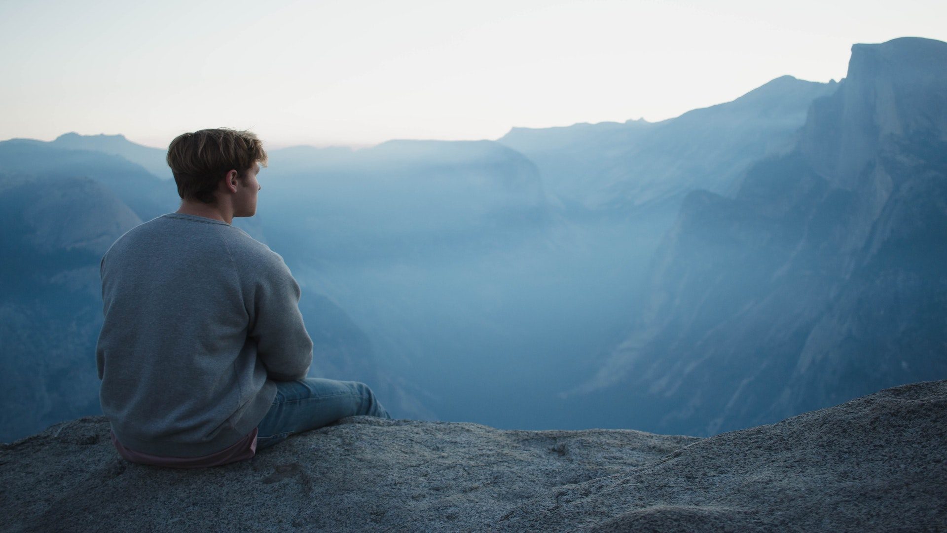 A man sitting on a rock overlooking mountains.