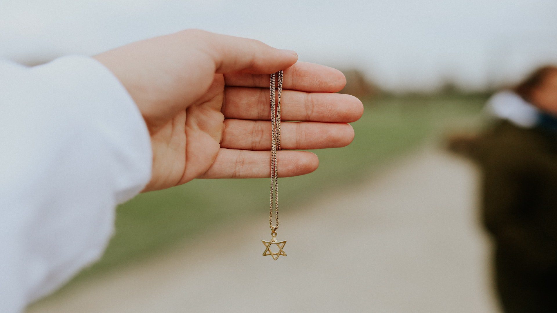 A person holding a necklace with the star of David.