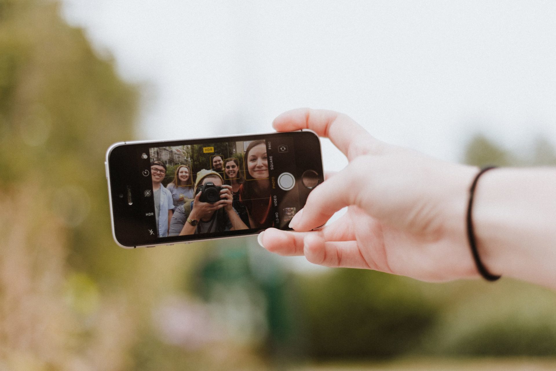 Person holding out their phone to take a selfie with their friends