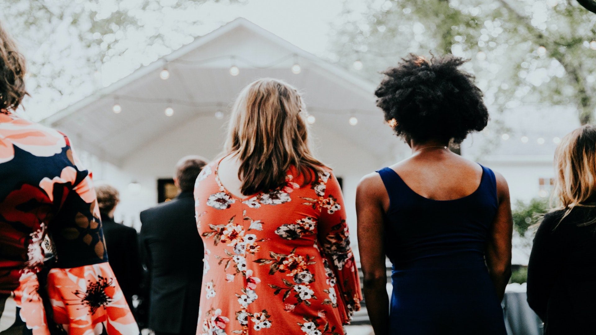 The backs of people standing in front of a church.