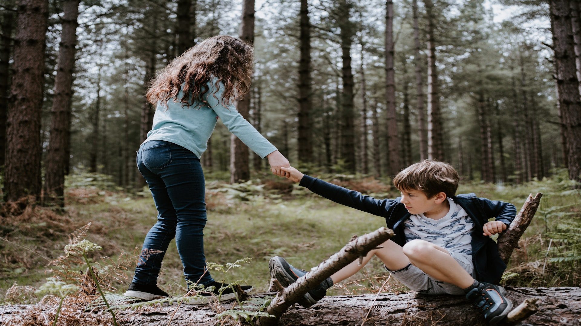 A boy and girl playing in a forest.