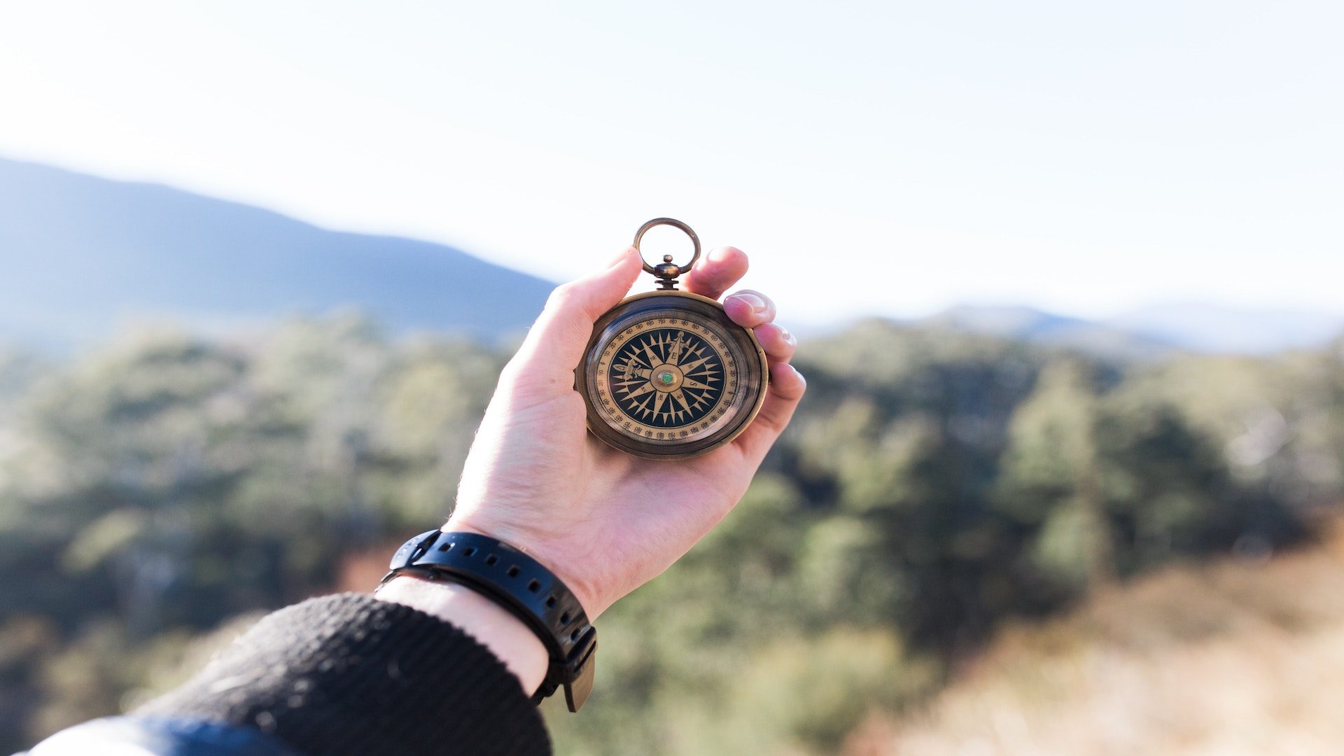 A person holding a compass outside.