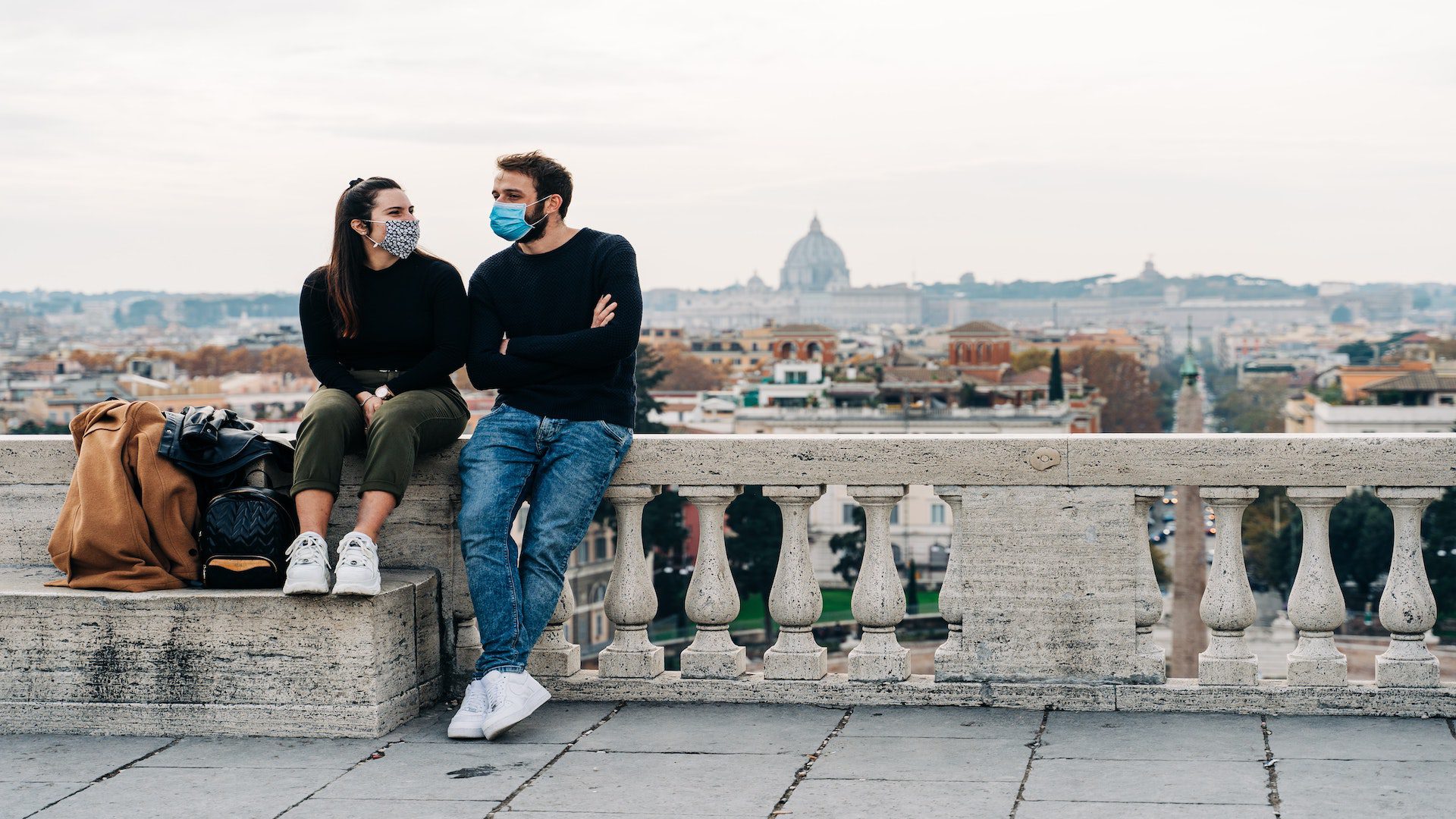 A man and woman city on a bench overlooking the city of Rome.