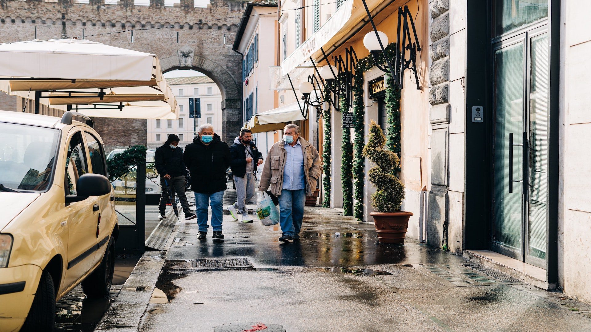 Men walking on a city street with face masks.