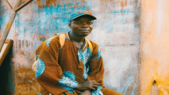 A man sitting in front of a blue and orange wall.