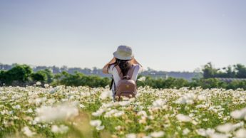 A woman standing in a field of white flowers.