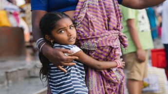 A young Indian girl hugging her mother as Christians share the gospel with Hindus in India.