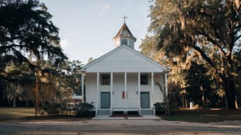 A white church surrounded by Savannah moss trees.