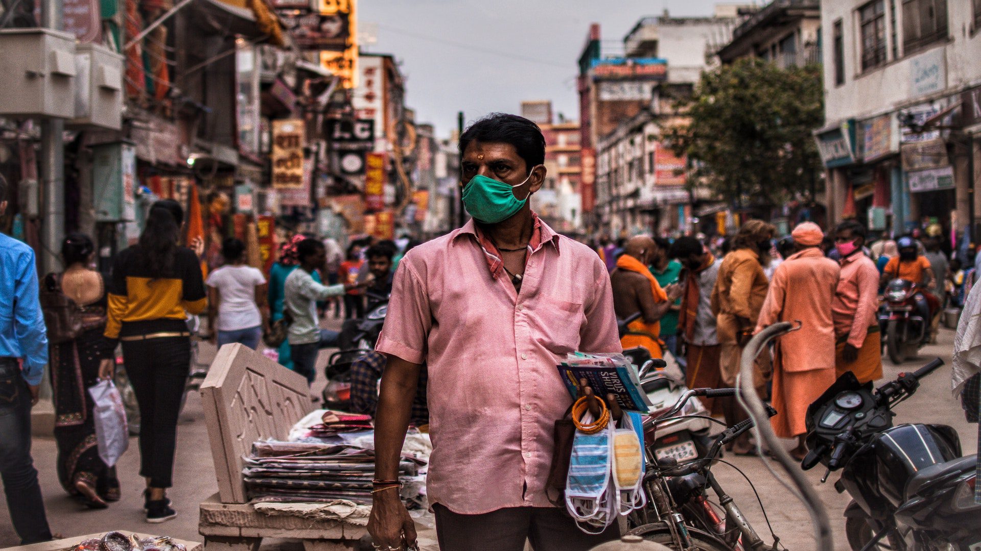 A man selling masks in a busy street in India during the pandemic.