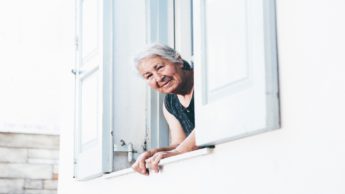 Elderly woman looking out of window.