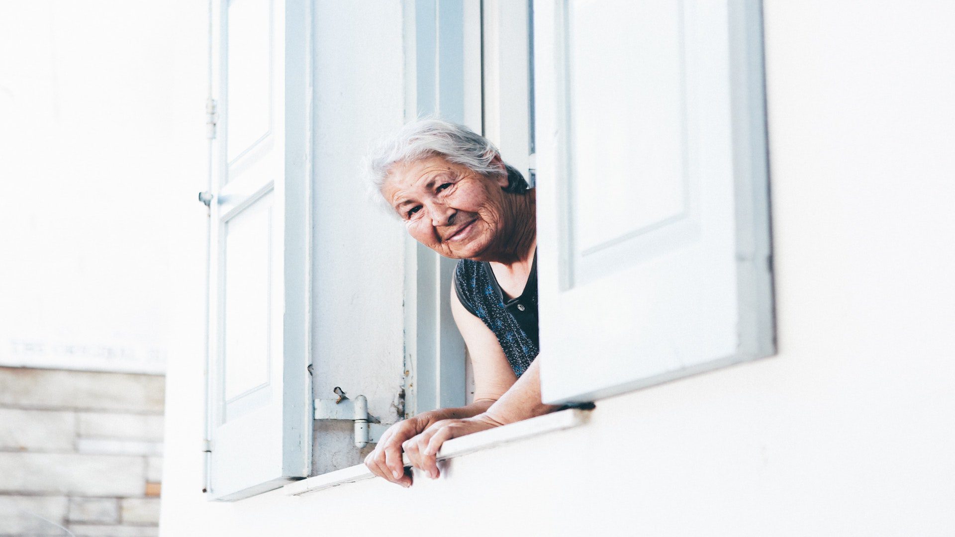 Elderly woman looking out of window.