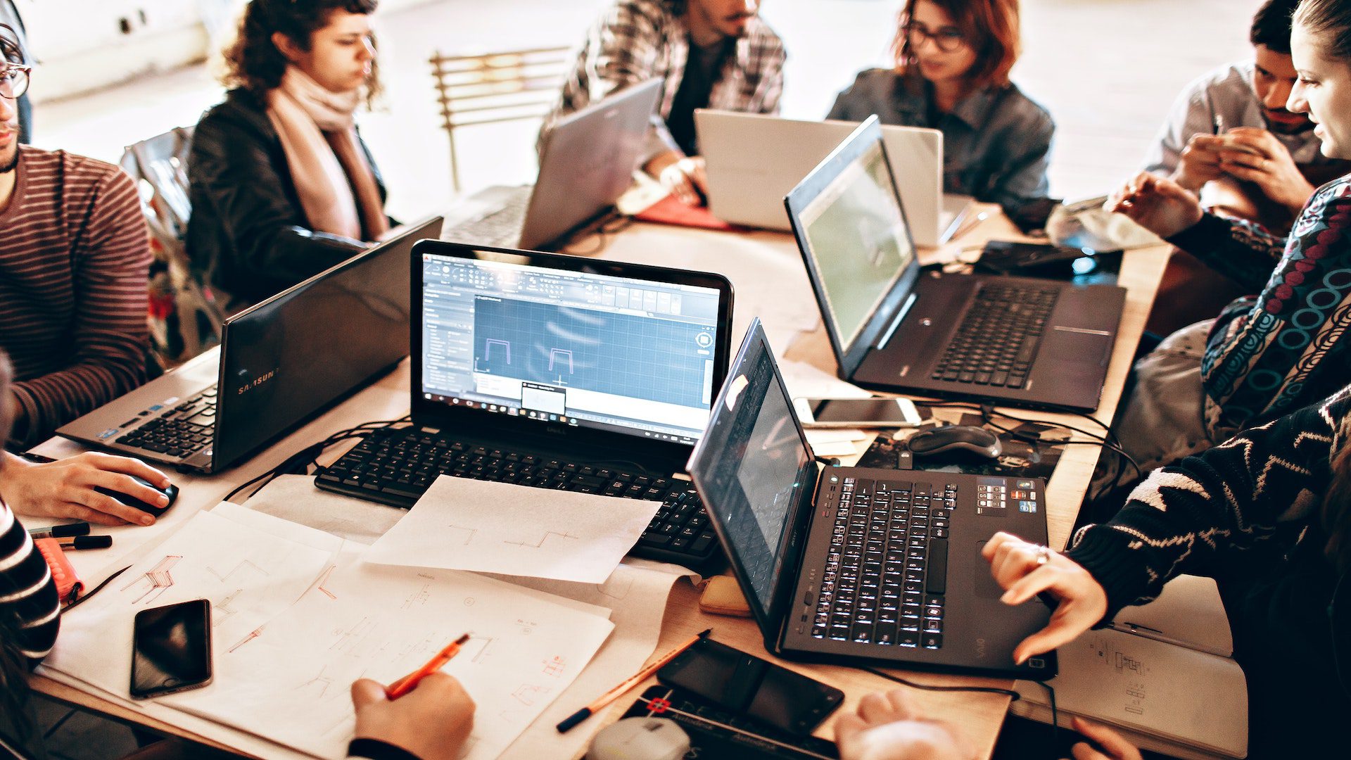 Group of people sitting at a table all on their laptops.