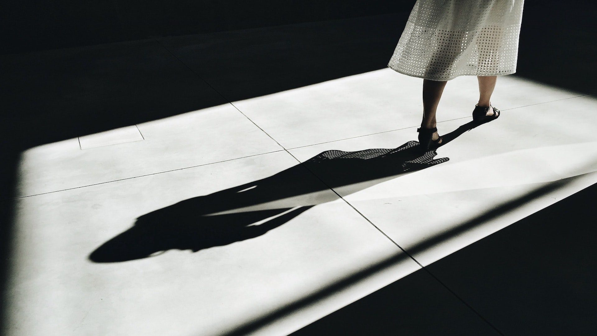 Shadow of a woman walking on a gray floor.