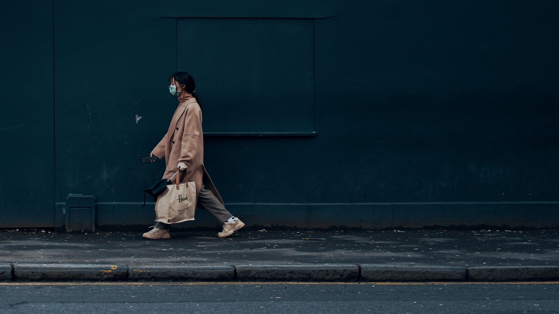Woman walking on a sidewalk wearing a face mask.