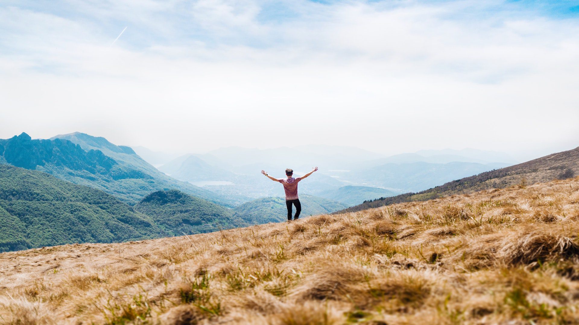Man walking on a hill with his arms raised.