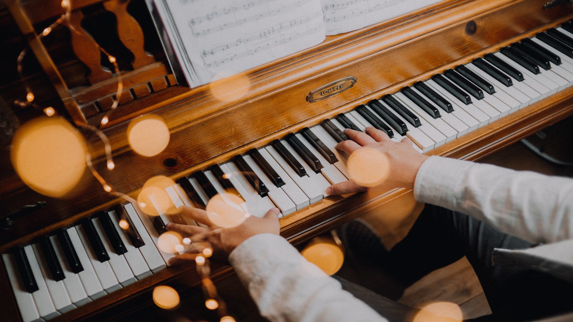 Person playing a piano with sheet music.