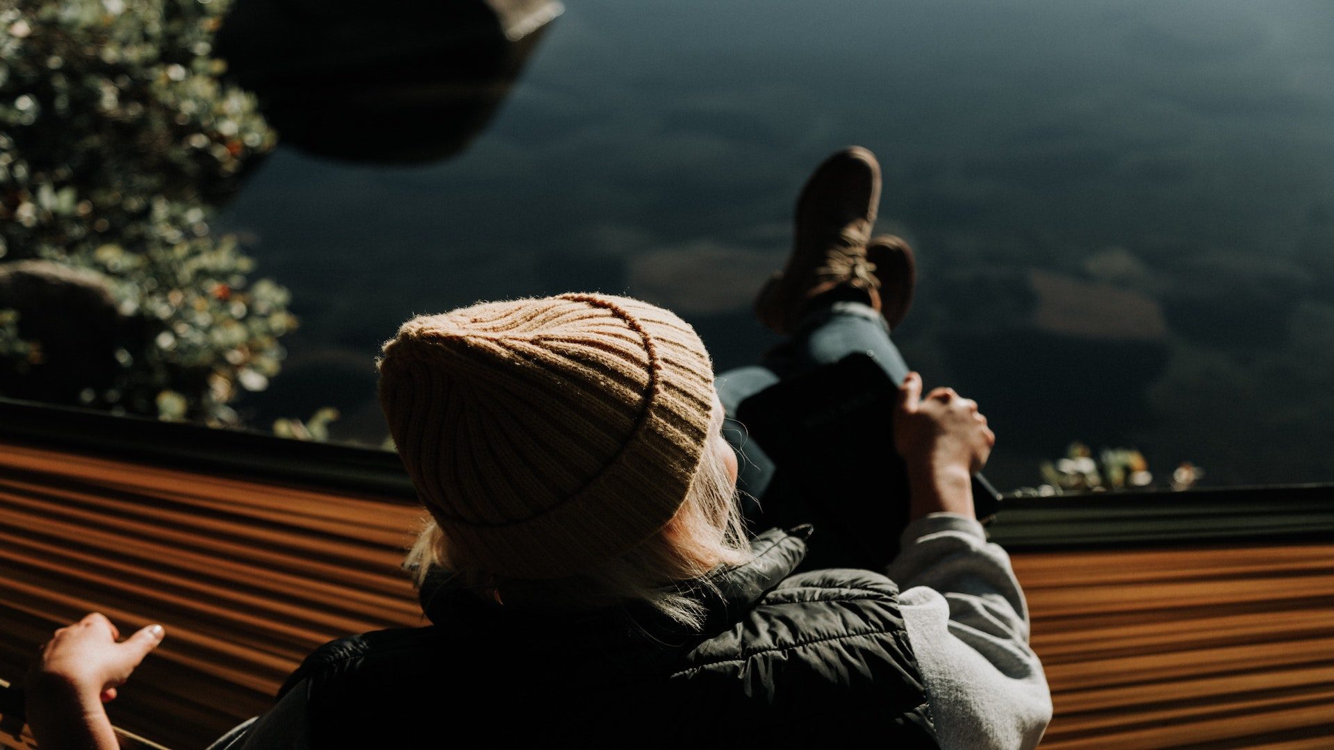 Woman sitting on a hammock near a lake.
