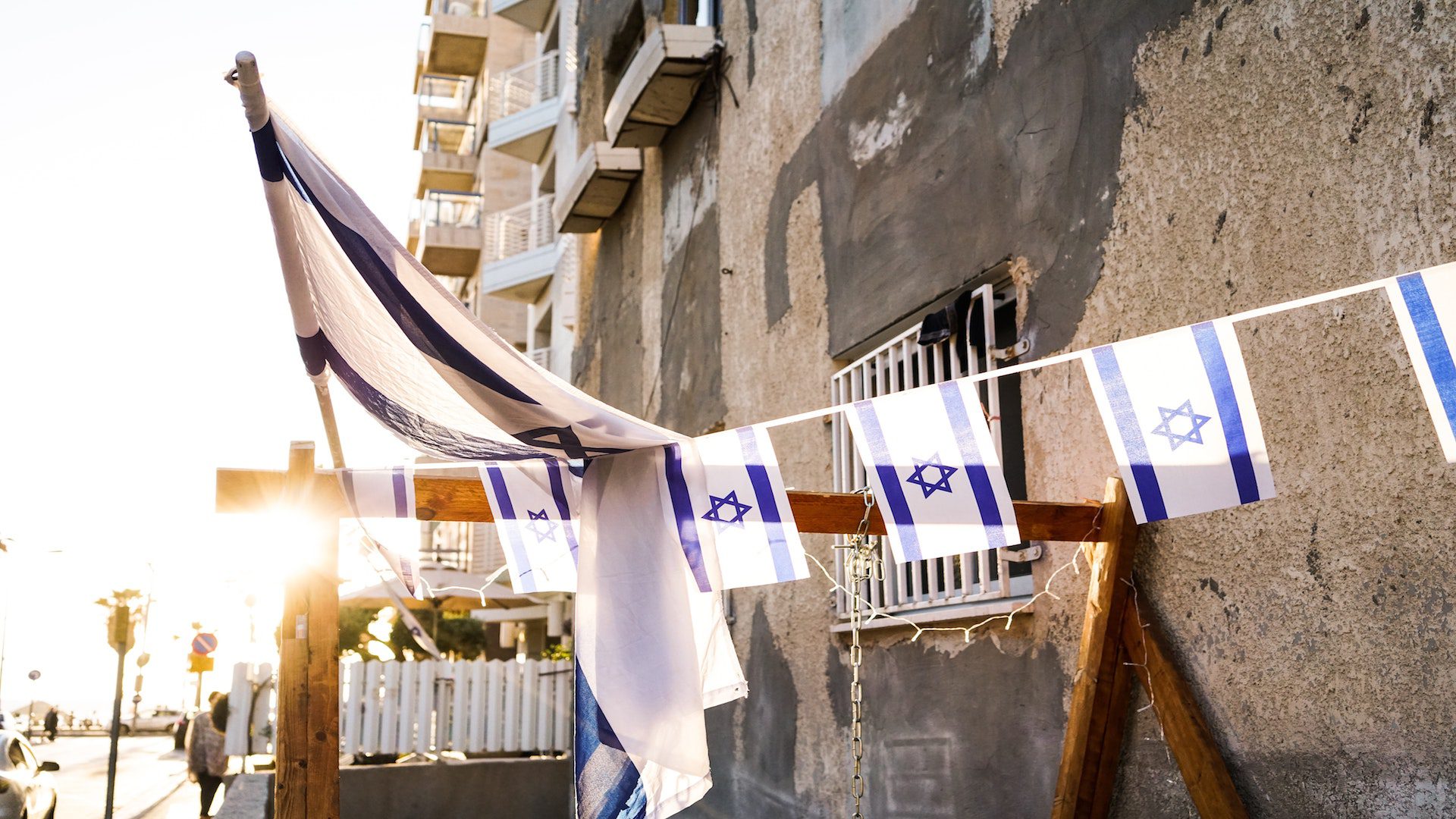 Israeli flags hanging outside a brown stone building.