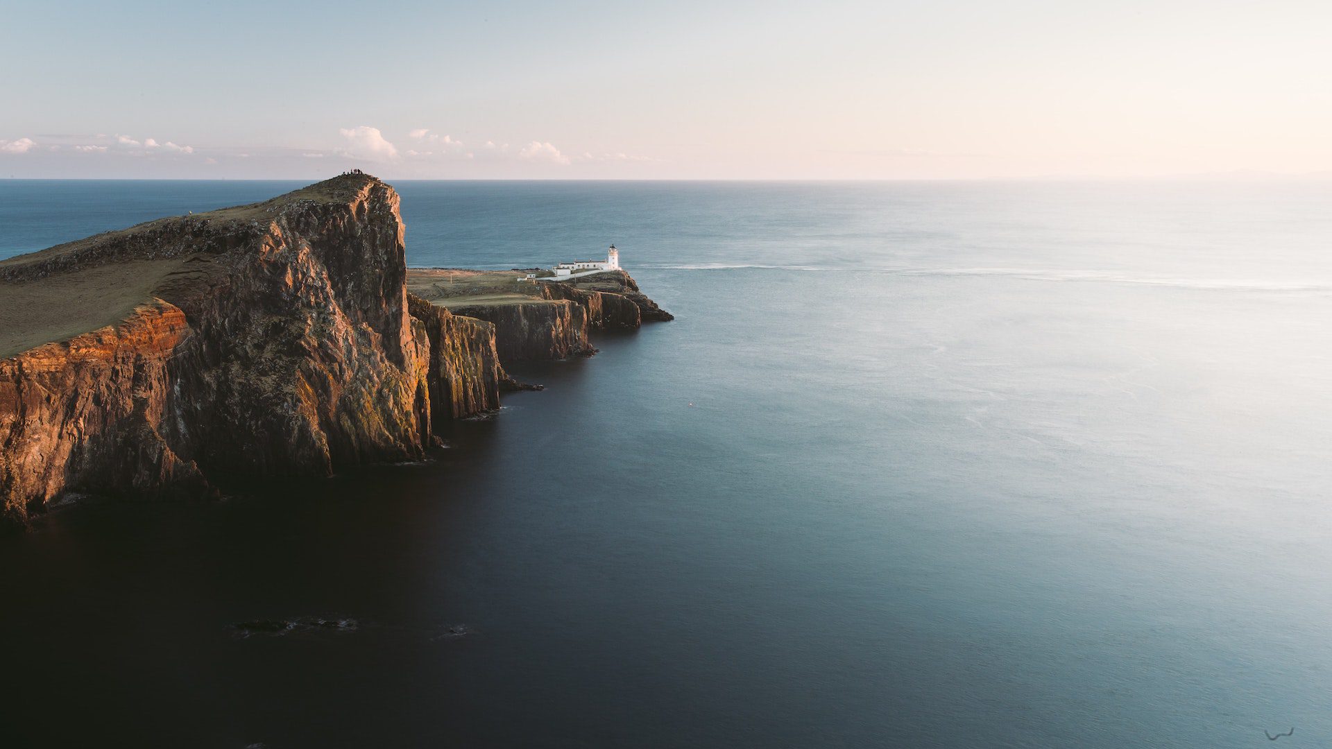 White lighthouse on cliff near ocean.