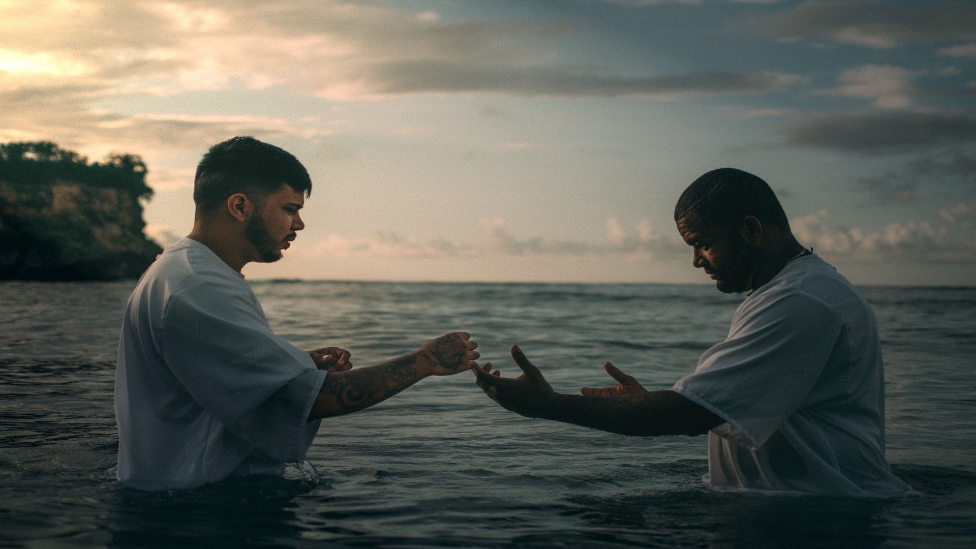 Two men in white shirts in a lake during a baptism.
