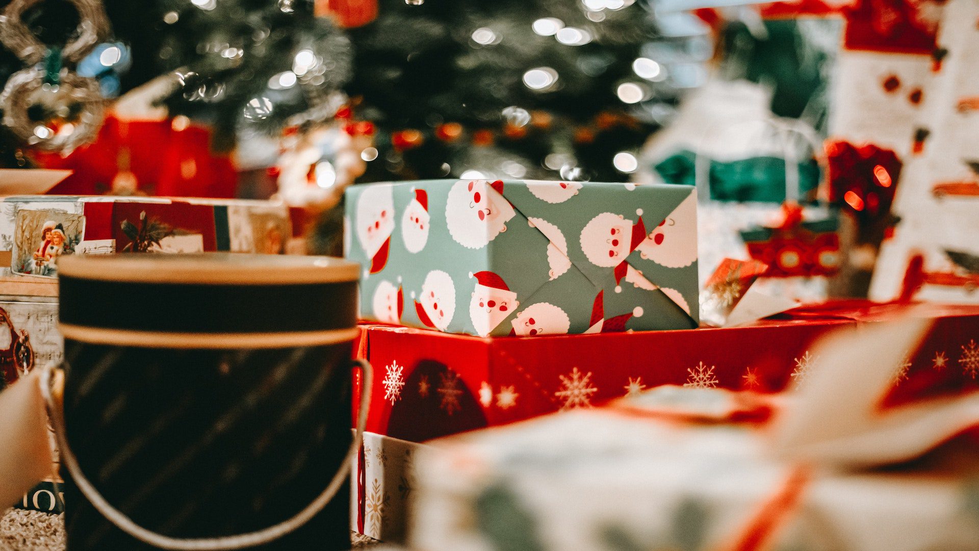 Boxes of wrapped Christmas gifts under a Christmas tree.