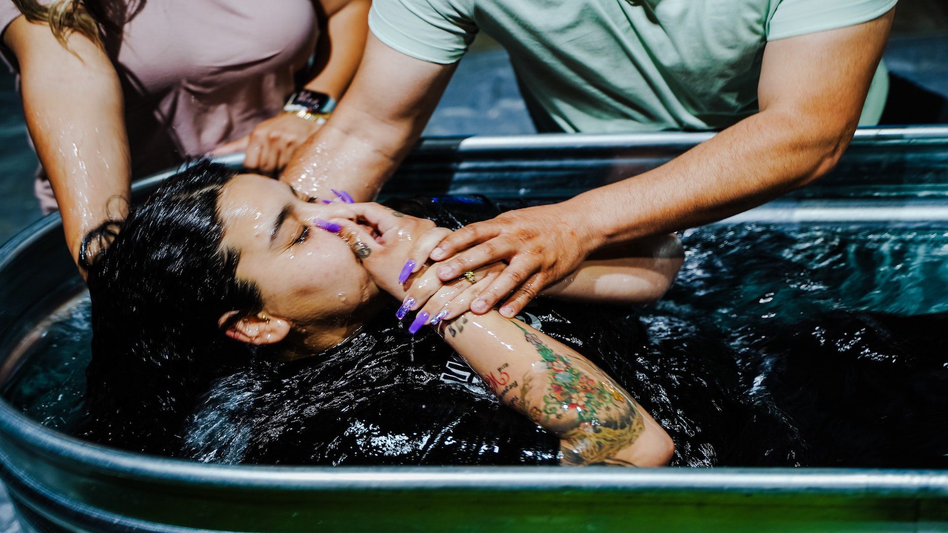 A woman rising up from water after being baptized.