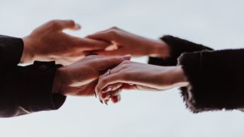 A man and woman holding hands outside.