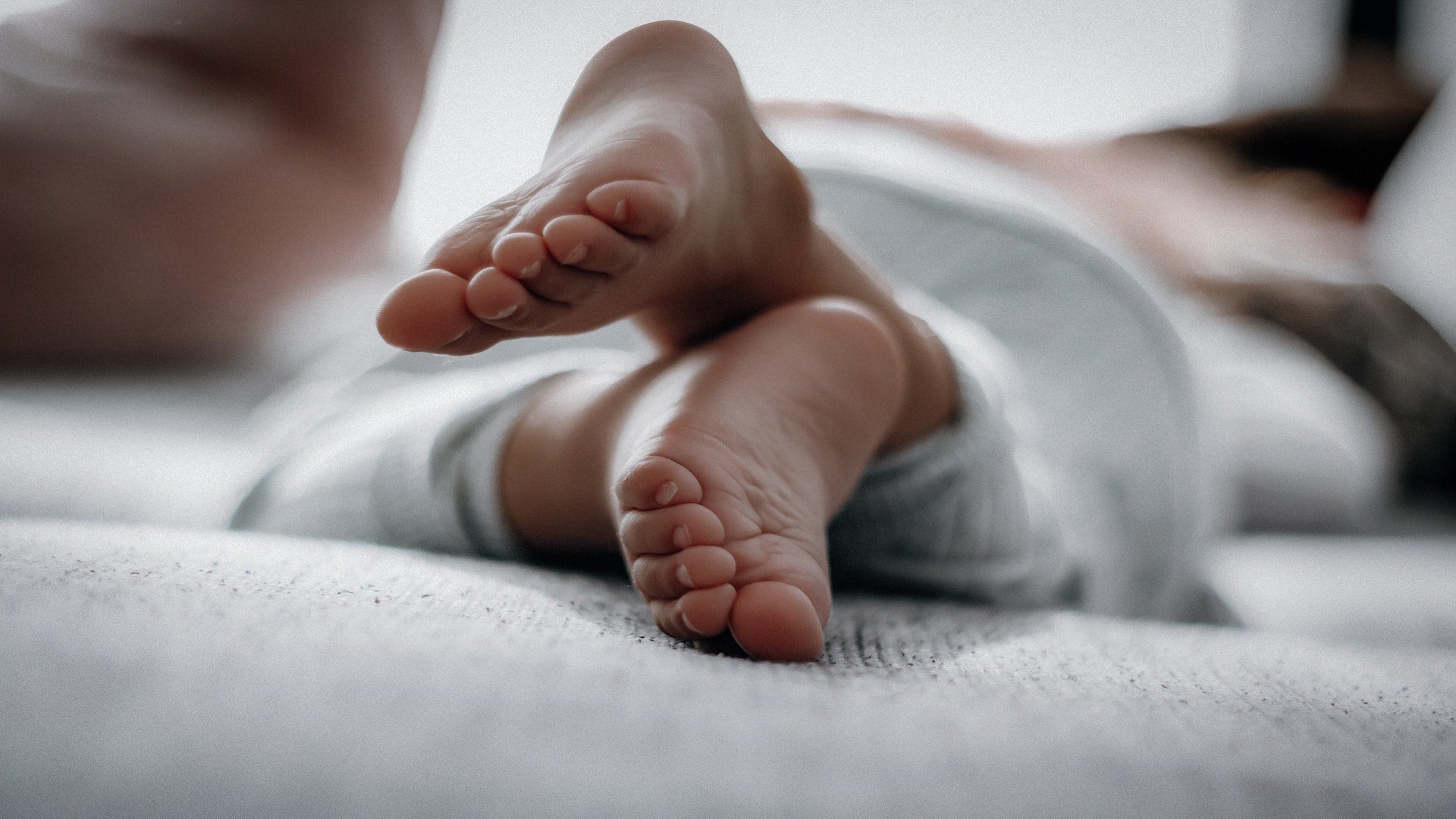 Feet of a baby in a gray outfit laying down.