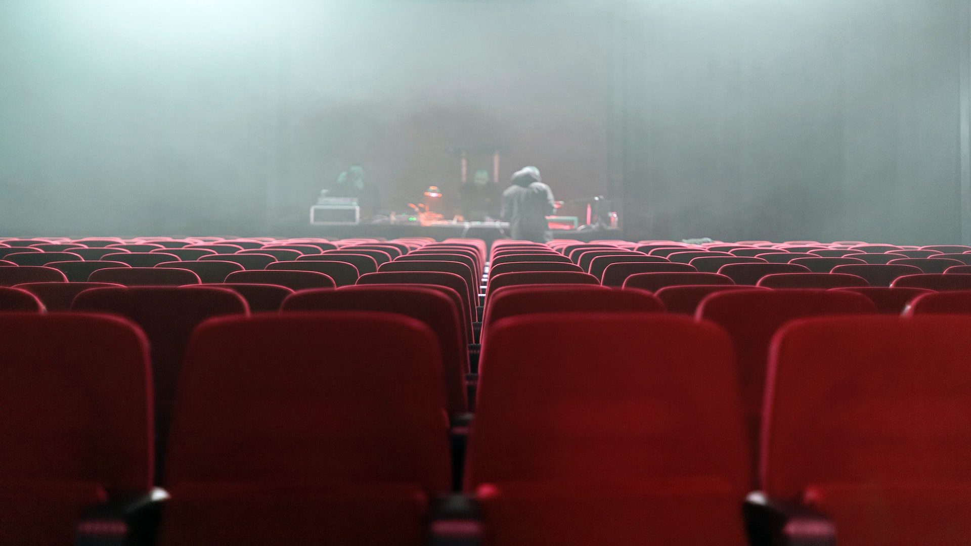 Red seats facing a stage in a theater.