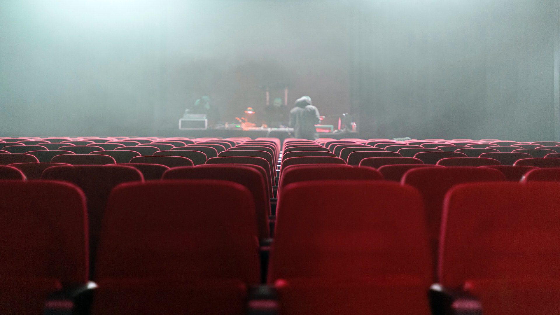 Red seats facing a stage in a theater.