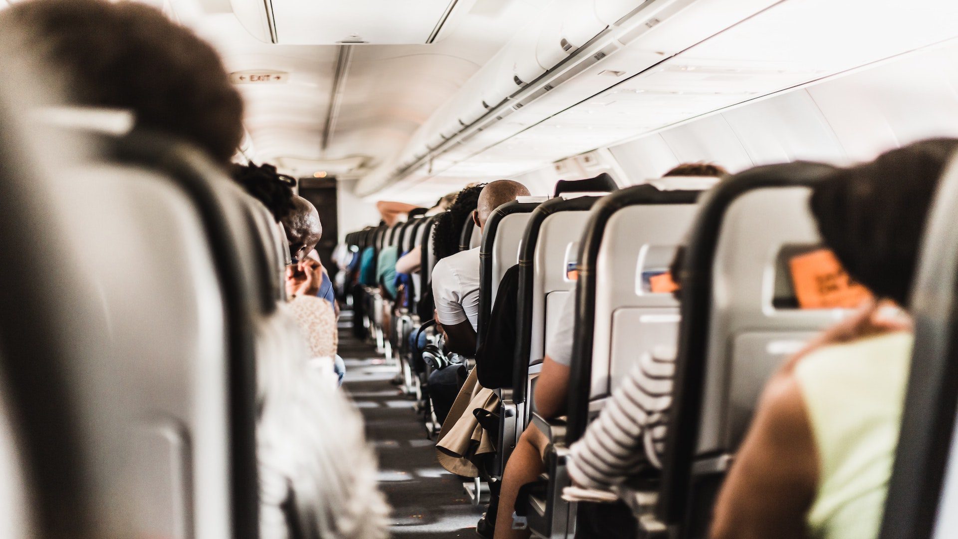 An aisle in a plane with people sitting in the seats on either side.