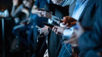 A line of people in suits on their cell phones with a blue light over them.
