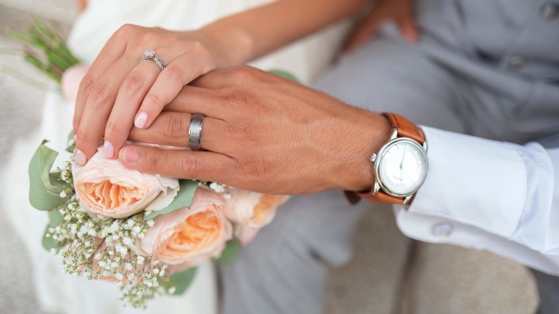 A man and a women with their hands on top of one another – you can see each of their wedding rings sparkle in the sun