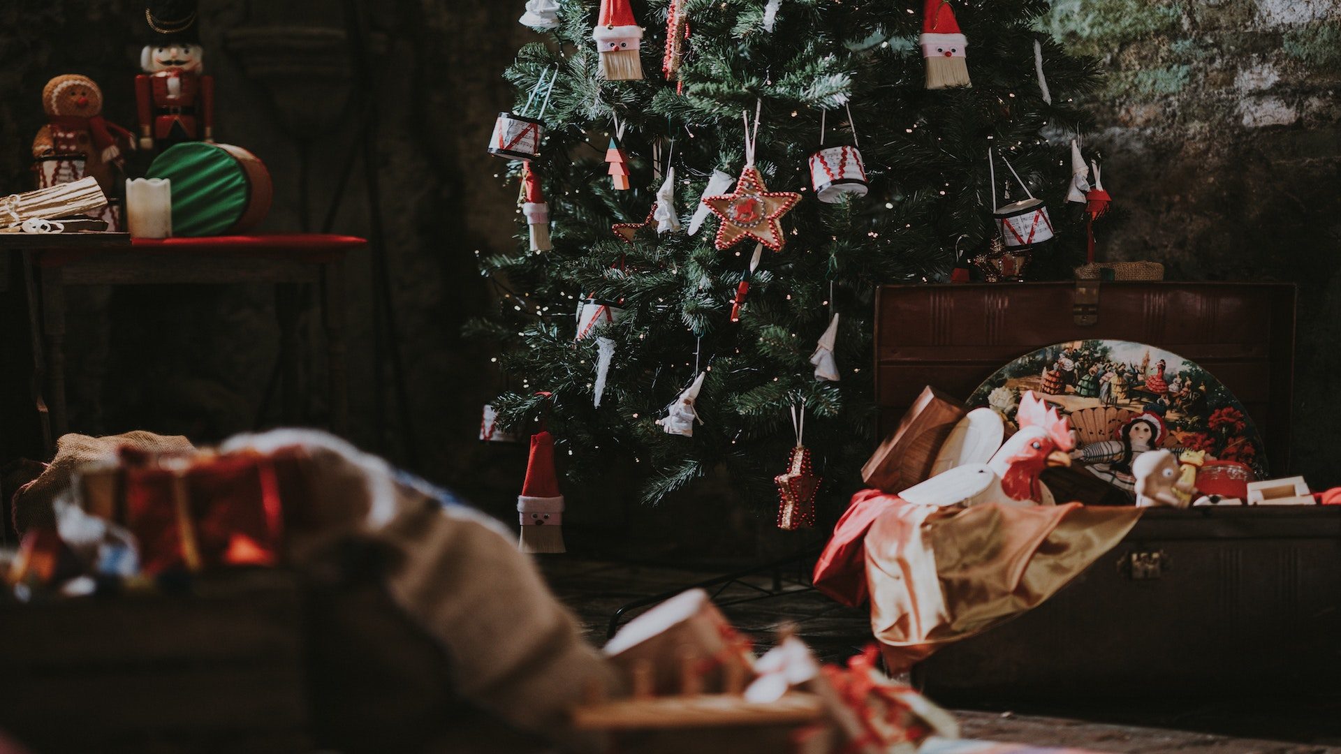 Decorated Christmas tree in a room surrounded by trunks filled with presents.