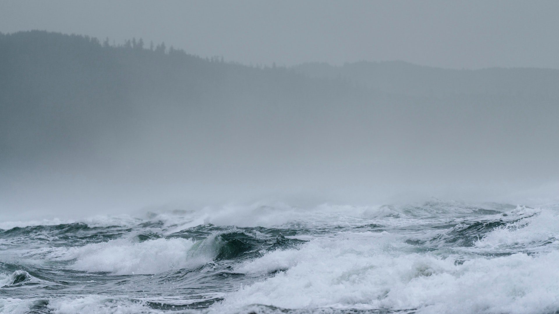 Ocean waves crashing on the shore on a cloudy and foggy day.