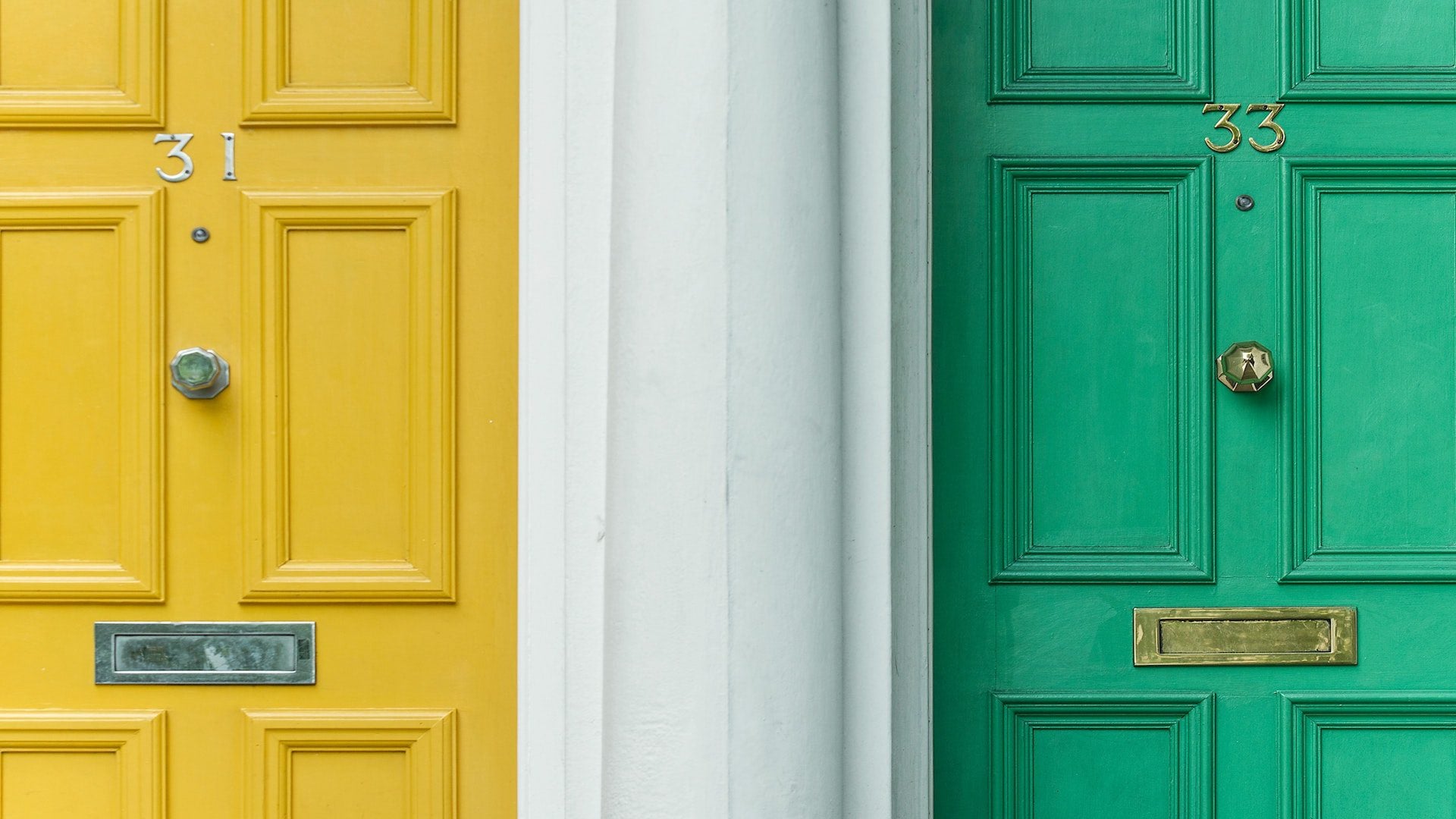 A yellow and a green door next to each other separated by a white wall.