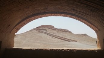 Stone arch in Iranian desert with a sand hill with a staircase.