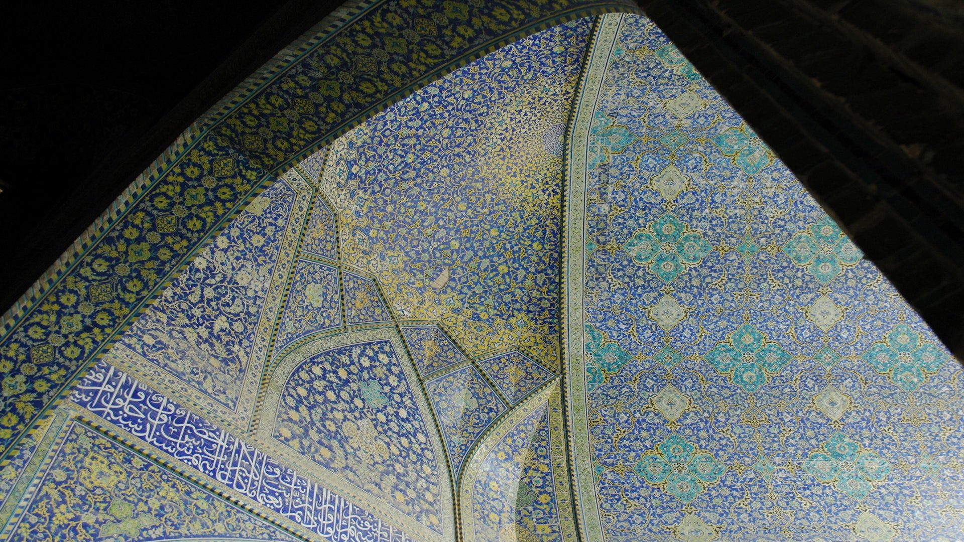 A blue, yellow and white floral painted dome in a mosque.