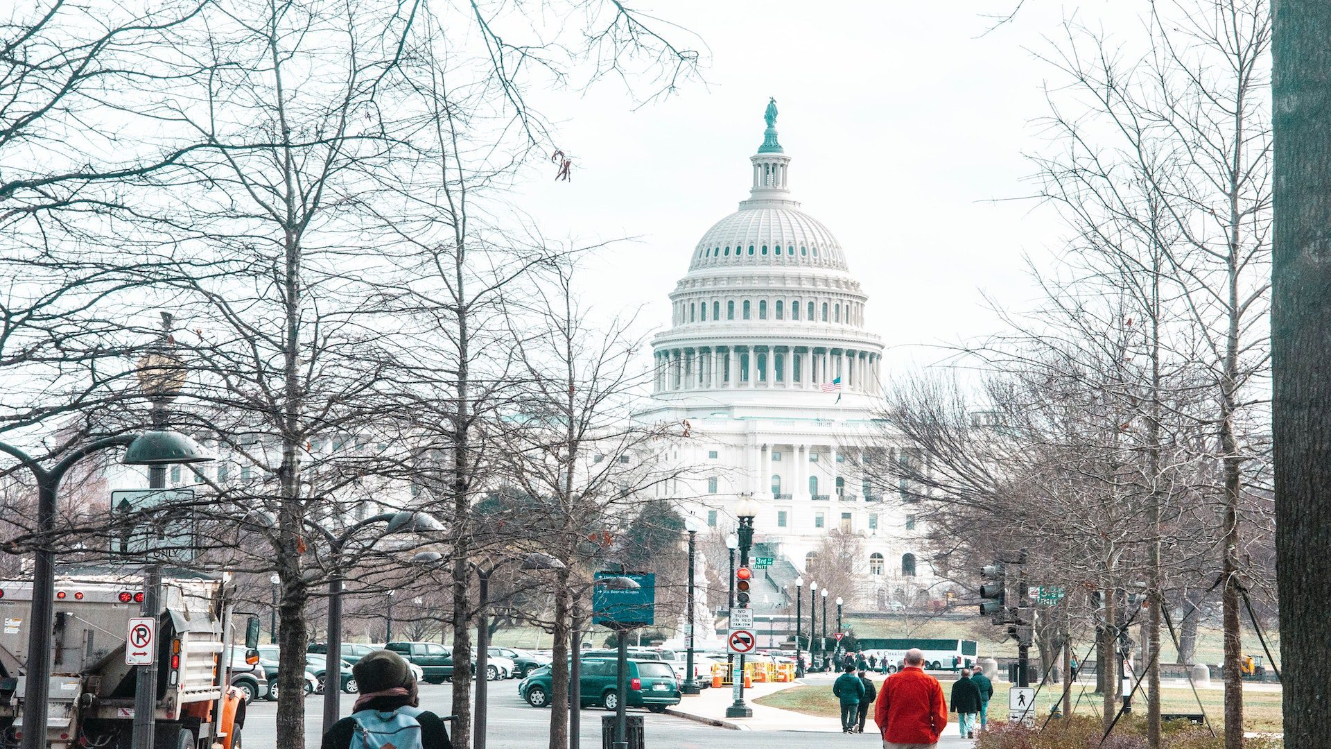People walking on a sidewalk during the winter in front of the Capitol building in Washington DC.