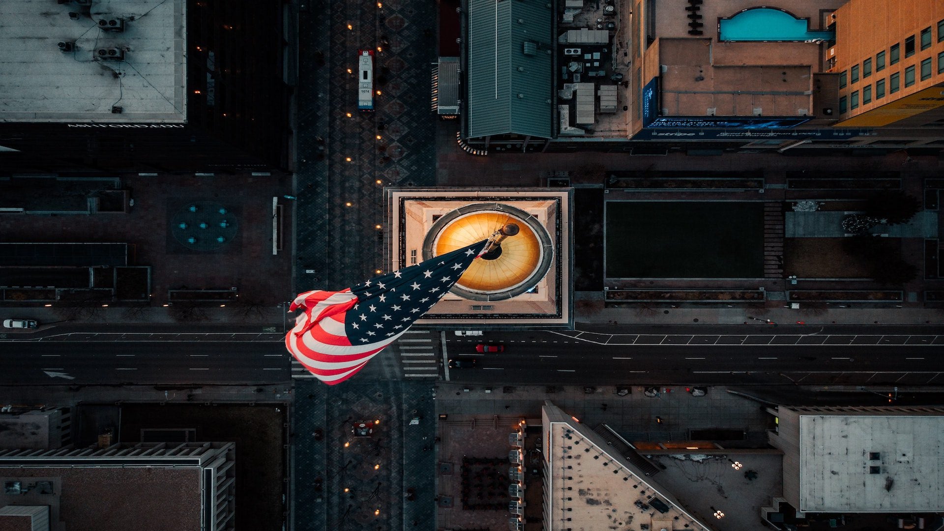 An aerial view of an American flag on top of a high rise building in a city.