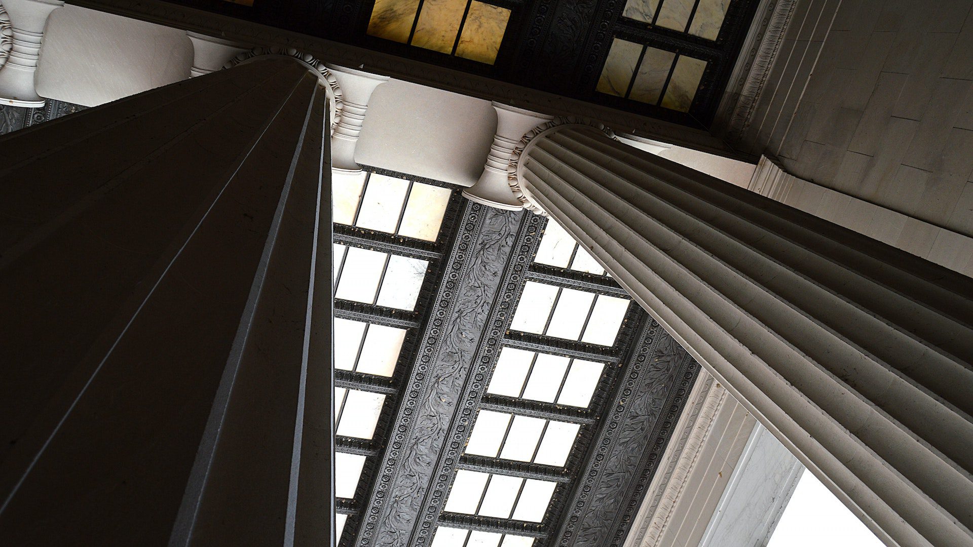 Low angle of white, marble columns and a black and white ceiling.