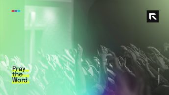 A room full of people lift their hands in praise to the Lord.