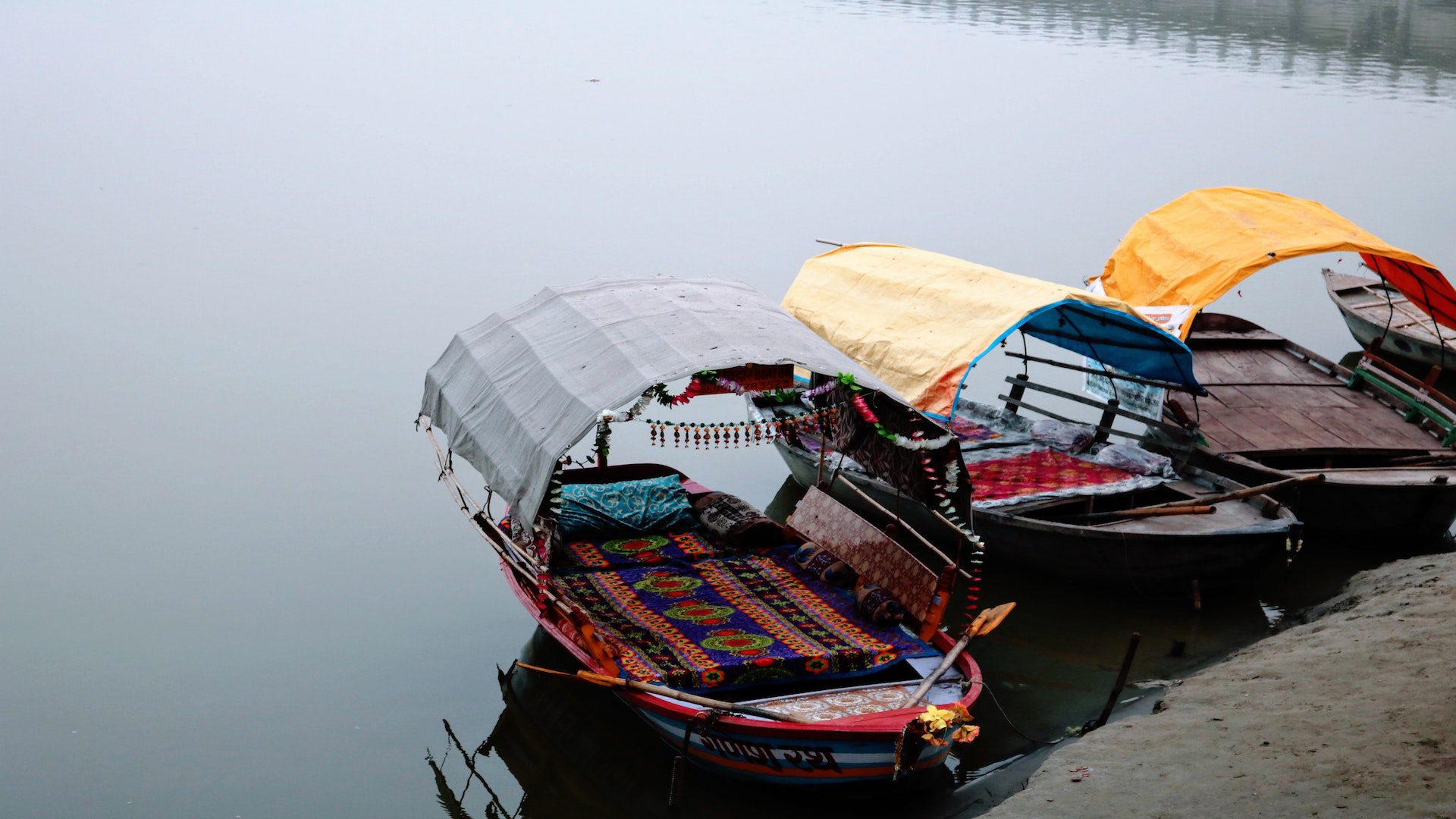 Covered rowboats with colorful textiles in a river.