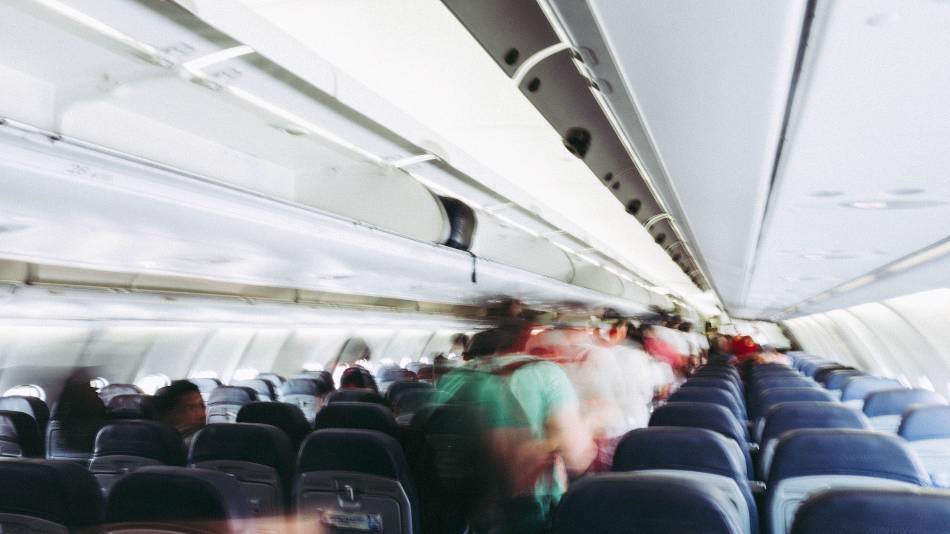 Blurred people walking in a plane aisle.