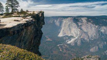 Rocky cliff overlooking a valley with trees.