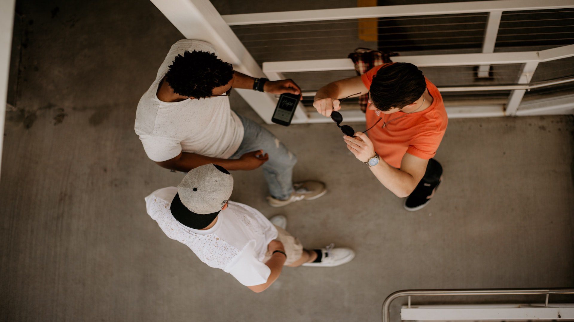 Aerial view of three men standing on gray concrete.