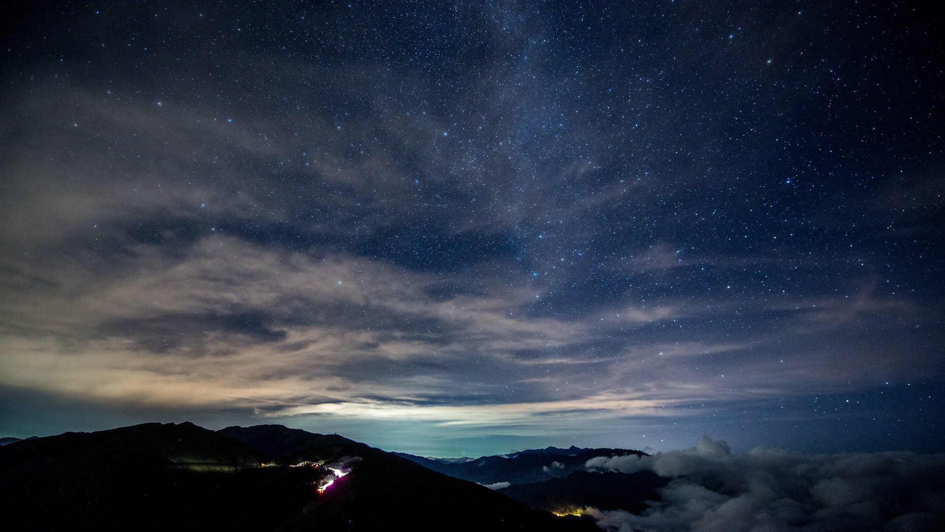 Blue, starry sky over silhouettes of mountains.